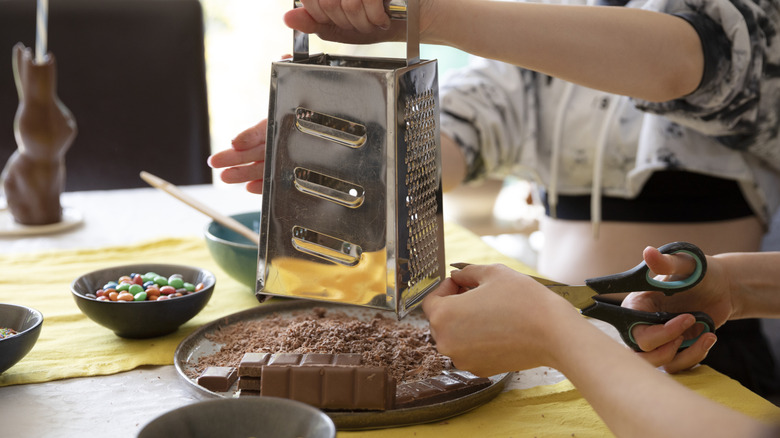 People using a boxed cheese grater for chocolate.