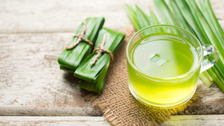 Glass mug of pandan juice next to pandan leaf