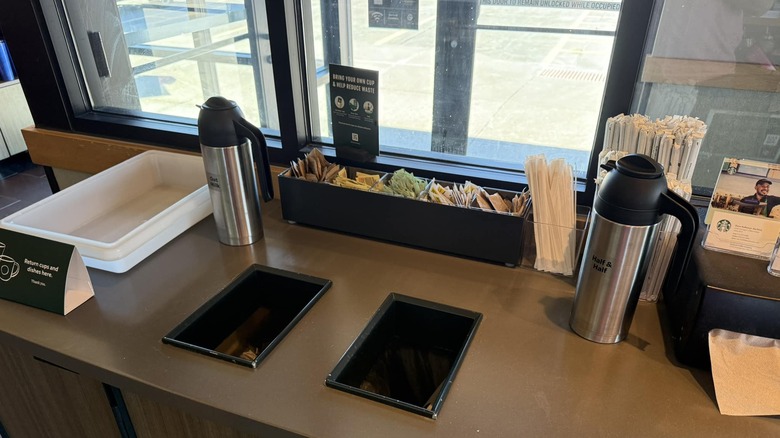 Two creamer caraffes sit on a Starbucks condiment bar