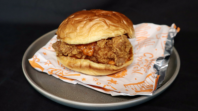 chicken sandwich on Popeyes wrapper on plate