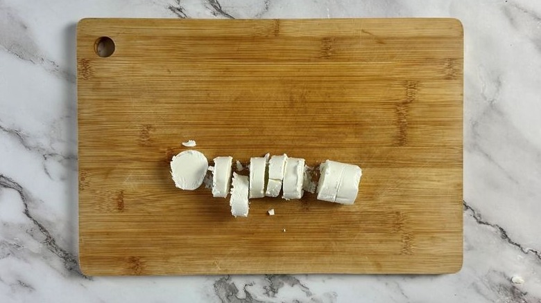 Goat cheese slices on cutting board