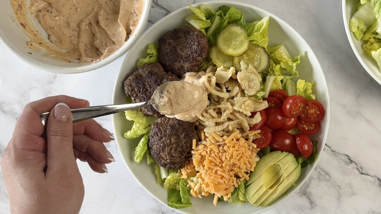 hand holding spoonful of dressing over salad