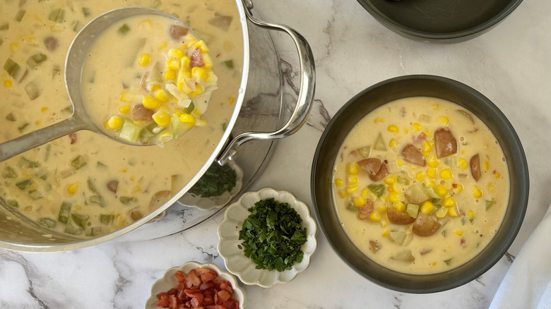 Ladle removing chowder from pot next to bowl of chowder