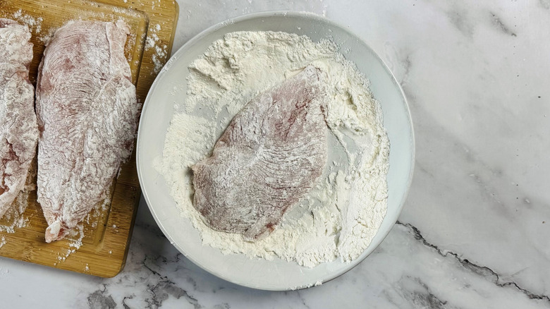 raw chicken dredged in flour on cutting board and dish
