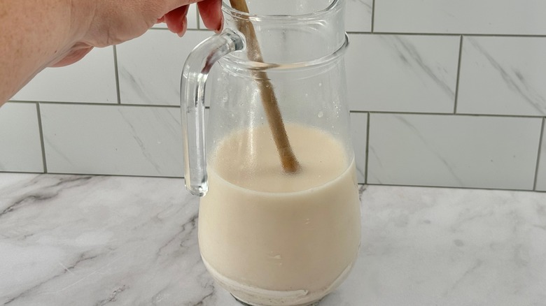 hand stirring cream-colored liquid