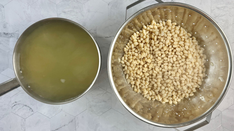 drained beans in colander with reserved bean water in saucepan