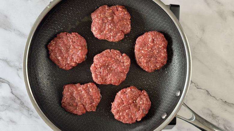 raw ground beef patties in frying pan