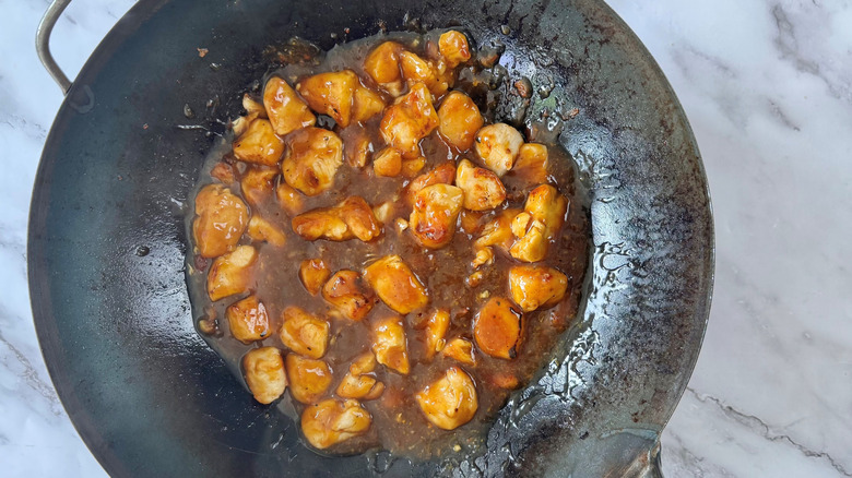 diced chicken with orange sauce in wok