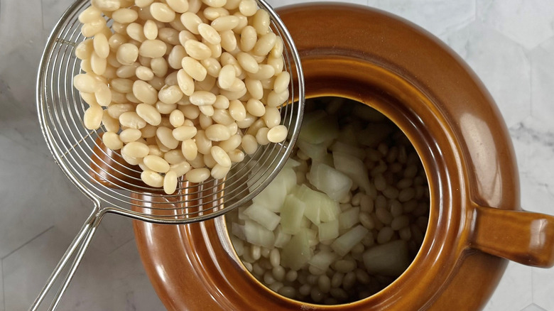 adding beans to dutch oven with onions