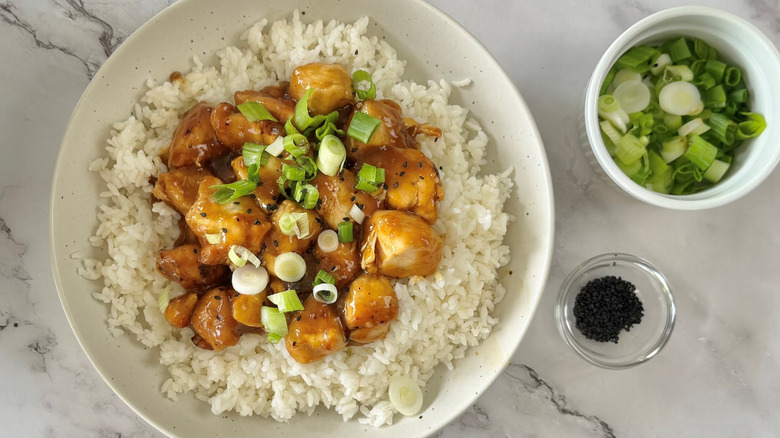 orange chicken with rice and scallions in bowl