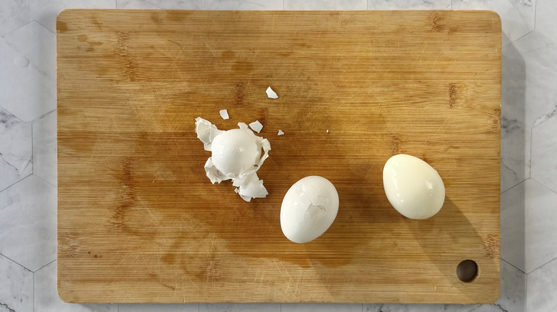 peeling hard boiled eggs on wooden board