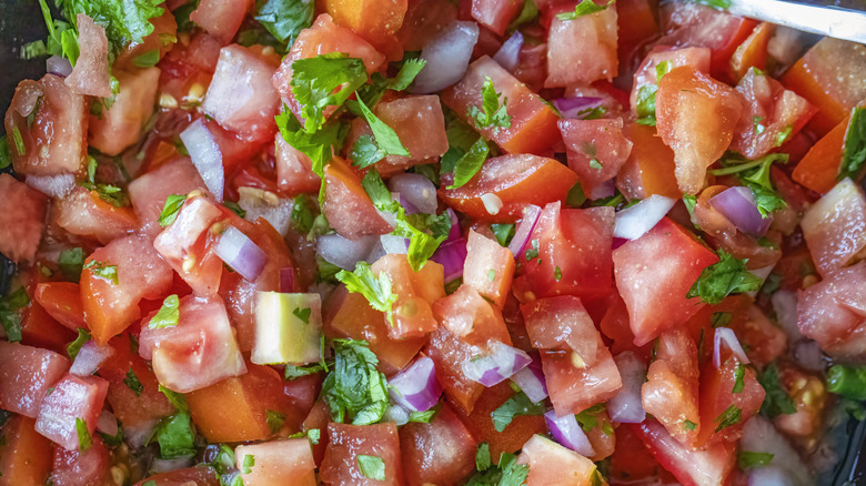 a close-up image of pico de gallo, including tomatoes, onions, and cilantro