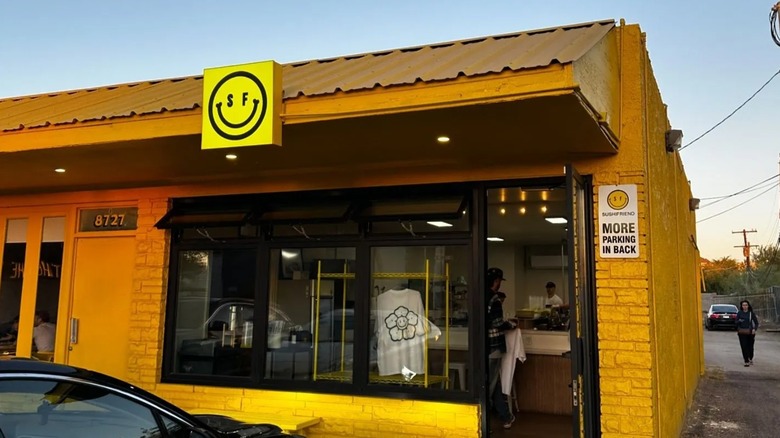 The exterior of Sushi Friend, it is yellow brick with a smiley face logo