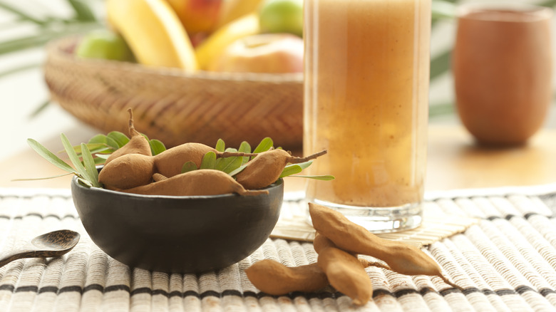 Bowl of tamarind pods in front of tamarind juice