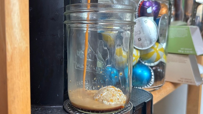 Nespresso machine brewing coffee into glass jar over latte bomb
