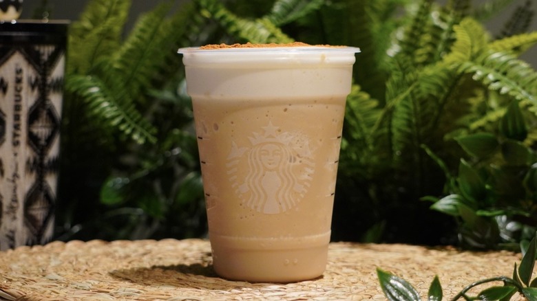 Brown Sugar Strato Frappuccino placed on a woven placemat in front of greenery