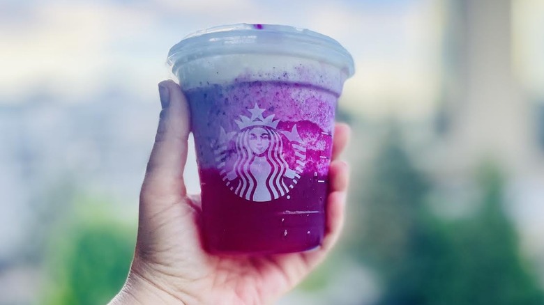 Hand holding Starbucks Dragonfruit glow-up drink