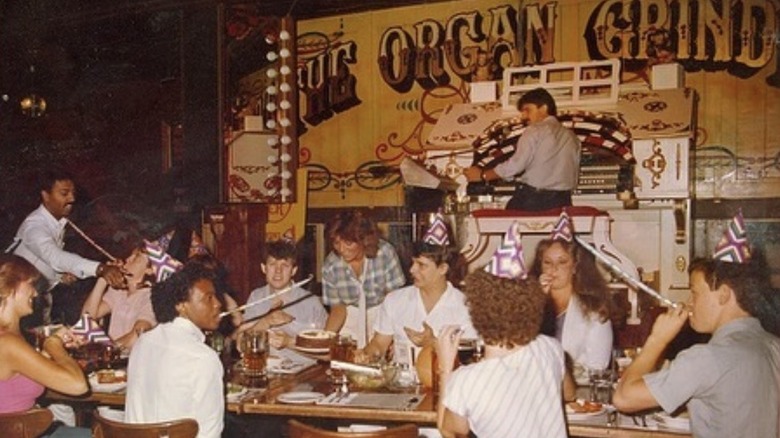Man sitting at organ while people eat pizza