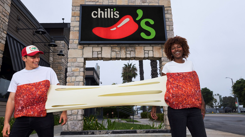 A couple wearing the two-person Chili's mozzarella stick cheese-pull costume