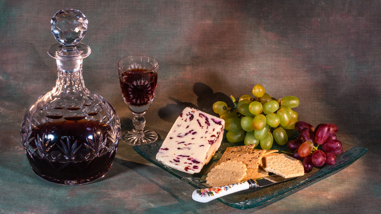 A glass of port alongside cheese and biscuits