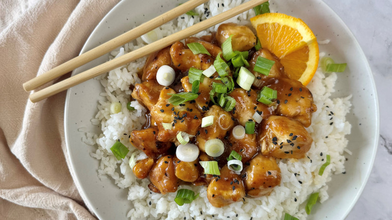 orange chicken with rice and scallions in bowl