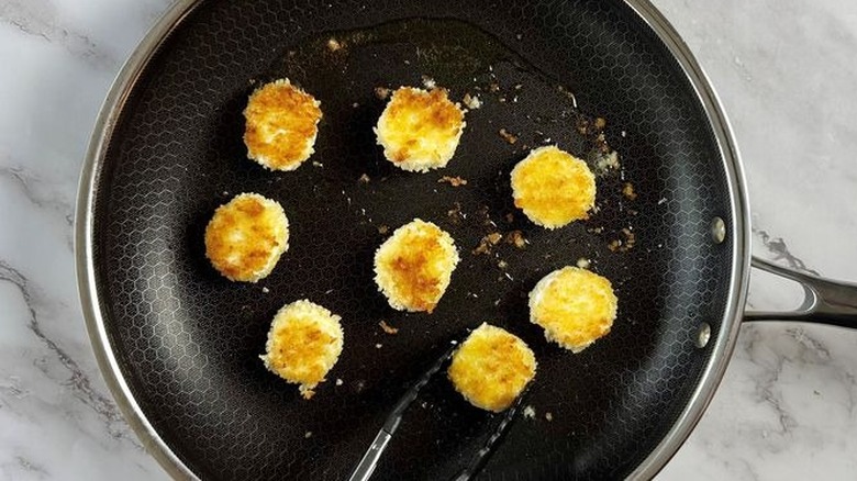 Breaded goat cheese slices in pan