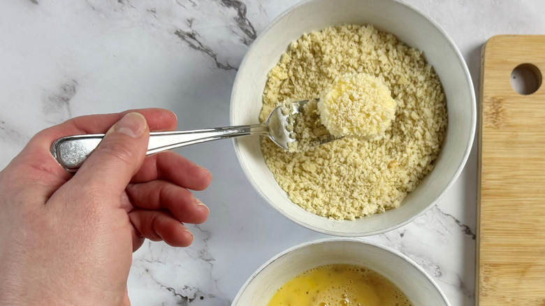 Fork holding cheese round over breadcrumbs