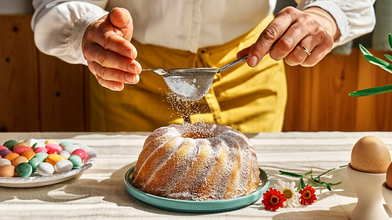 Chef sifting sugar onto a bundt cake