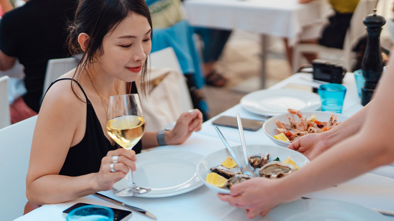 A young diner anticipating a delicious French meal while holding a glass of wine