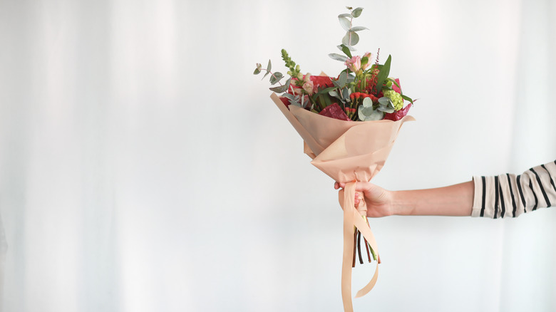 Someone handing over a bouquet of flowers without a vase