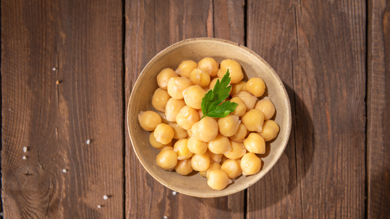 Bowl of cooked chickpeas on wooden table